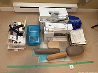 Overview of Bernina sewing machine, accessories, plastic tote of sewing supplies, books, cutting mats and pressing tools on floor