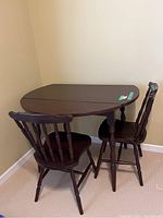 Table and two chairs set positioned in corner, showing overall item arrangement and condition.