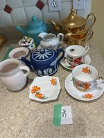 Overview of the set displayed on countertop including tea pots, tea cups, saucers, small dish, creamers, and sugar pot.