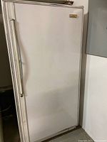 Photo of the upright freezer exterior showing white door with vertical stainless steel handle.