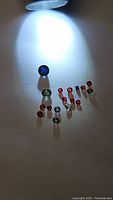Photo of all sapphires in parcel, arranged on a flat surface with a spotlight, showing variety of colors and shapes.