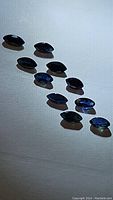 Top view of a parcel of 12 marquise cut sapphire gemstones laid out in rows on a white surface, showing size and shape consistency.