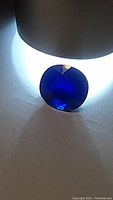 Loose oval sapphire on white background under direct lighting showing color and cut