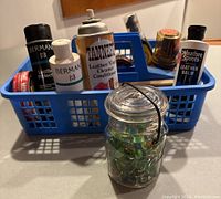 Blue basket with assorted shoe polish and leather care products, and small Ball glass jar with marbles