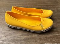 Side view of the left yellow Crocs shoe showing the profile, texture, and logo on the back heel.