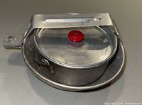 Nesting vintage aluminum camping mess kit with covered pot, skillet, pan, handled cup and folding cup all compact together showing red knob on pot lid.
