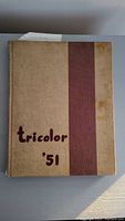 Front cover of a hardcover beige yearbook with a dark red vertical stripe and title 'tricolor '51' handwritten on the front.