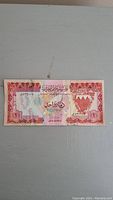 Front side of the 1 Dinar banknote showing Arabic text, map outline and decorative patterns