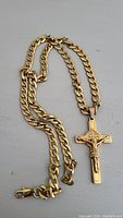 Full view of the gold plated curb link chain and crucifix pendant showing the chain length and clasp.