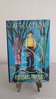 Front cover of Affliction by Russell Banks showing book standing on a small display stand.