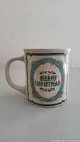 Front side of the ceramic mug showing the Merry Christmas wreath design