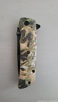 Closed view of the folding pocket knife showing the camouflage handle and locking screws.