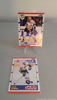 Two Mario Lemieux hockey cards displayed vertically, one upright on stand and one laid flat