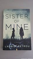 Front cover of 'Sister of Mine' by Laurie Petrou showing title, author, and silhouetted figures.