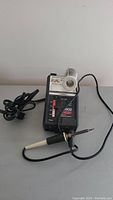 Aoyue 909B soldering station including soldering iron, attached holder with coil, power cord, and temperature slider control.