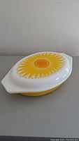 Casserole dish with lid closed, showing bright yellow Daisy pattern on lid.