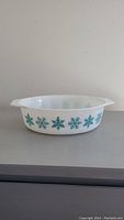 Front view of the white Pyrex oval casserole dish with turquoise snowflake pattern, showing overall shape and design.