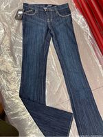 Full view of dark blue denim low rise flare jeans with tags attached.