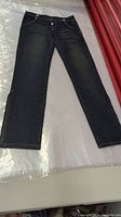 Full length front view of dark wash jeans showing button fly closure and tapered legs