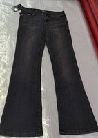 Full view of faded black bootcut jeans laid flat showing front side