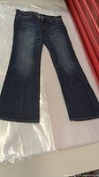 Full view of blue bootcut jeans laid flat, displaying flare leg shape.