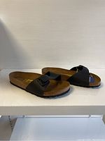 Side view of black Birkenstock ladies sandals showing cork footbed and adjustable strap.