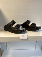 Side view of pair of black ladies slide shoes with two Velcro straps each, showing chunky sole and wide fit