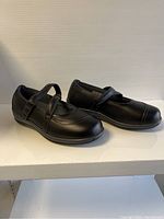 Pair of black Orthofeet Mary Jane shoes shown from side angle.