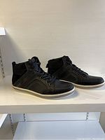 Side angled view of the pair of black Steve Madden high-top sneakers showing details of side panels and soles.