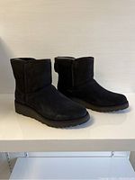Side angled view of black UGG boots showing short shaft and flat sole.