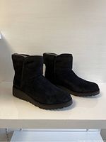 Side and angled view showing entirety of both black suede boots with low heel and rounded toe.