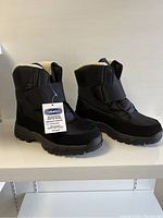 Pair of black waterproof winter boots shown from side angle with original tags attached.
