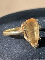 Angled view of ring showing pear-shaped stone and prong setting