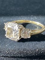 Clear detailed close-up of the ring showing the rectangular center stone and two smaller round stones on either side with gold filled band.