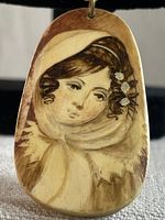 Close-up photo of the front of the hand painted pendant showing the detailed portrait of a French aristocrat woman in a headscarf with flowers.
