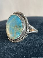 Front view of Navajo turquoise ring showing irregular oval turquoise stone with natural veins set in bezel surrounded by rope silver edging.