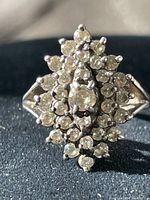 Close-up front view showing cluster of clear CZ stones in a raised prong-set design on sterling silver ring.