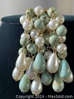 Close-up front view of the vintage brooch showing cascading faux pearl and turquoise teardrop beads attached by gold-tone links.