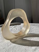 Photo showing side angle of the translucent off pink white Lucite cuff bracelet, highlighting the thickness and organic triangular shape.