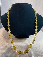 Full view of the amber glass and clear crystal beaded necklace displayed on black stand.