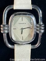 Front view of silver-tone Caravelle wristwatch showing rectangular face with minimal hour markers and light calf skin strap.