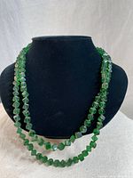 Full view of vintage flapper necklace with two loops, showing the translucent green cubed beads on black display.