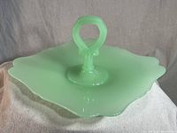 Full view of the vintage Fenton jadeite glass serving dish showing its square shape with rounded corners and the tall ribbed handle at center.