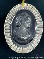 Close up photo of vintage black Bakelite cameo with a female profile, surrounded by etched Lucite border