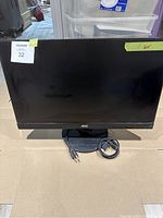 Front view of AOC 24-inch monitor showing screen, base stand, power cable, and HDMI cable on a cardboard surface.