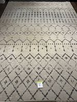 Full view of the off-white area rug with grey geometric patterns, showing overall design and scale.