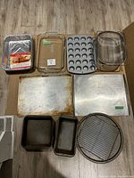 Full view of baking items including disposable aluminum pan, glass baking dishes, muffin pan, cooling rack, loaf pan, and metal baking sheets.