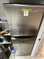 Front view of a stainless steel Danby refrigerator with top freezer and bottom fridge doors.