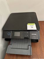 Front-facing view of Epson XP-6100 printer showing output tray extended and control panel with buttons and screen.