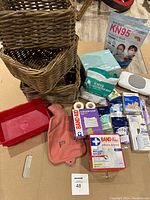 Photo of assorted storage baskets stacked and first aid items grouped beside them including KN95 masks and a pink hot water bottle